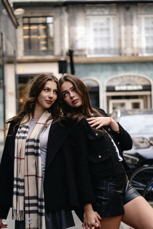 Two women standing next to each other in front of a building